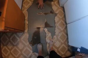 Původní podlaha v kuchyni s poškozenými dlaždicemi a viditelným opotřebením