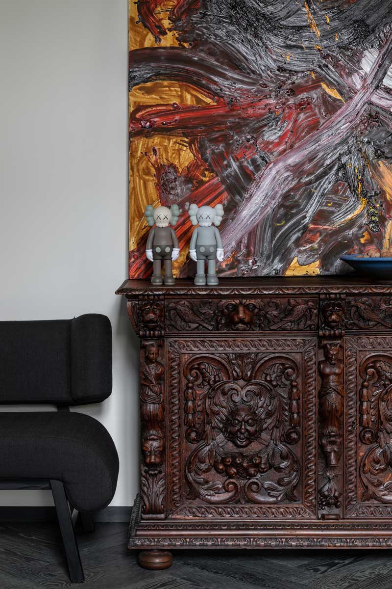 Vyřezávaná historická skříň s moderními dekoracemi a uměleckým obrazem