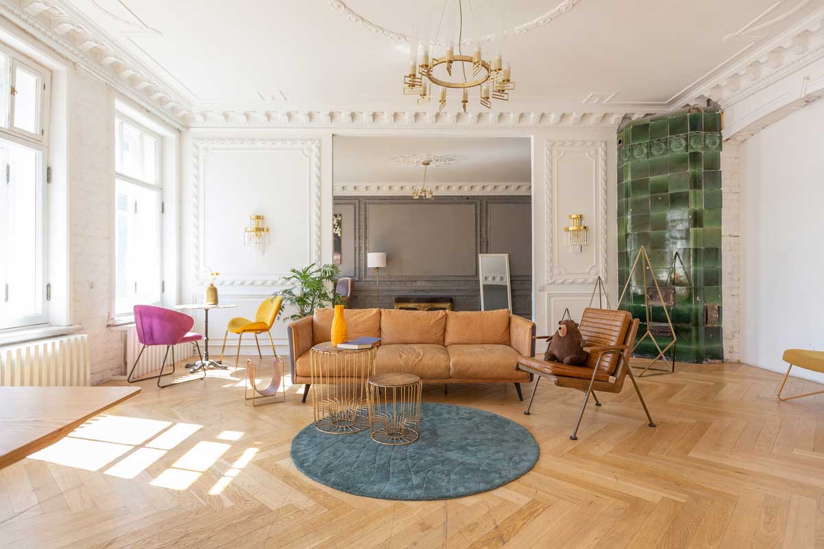 Historický interiér s bohatým štukem na stropě a stěnách kombinovaný s moderním nábytkem a barevnými akcenty