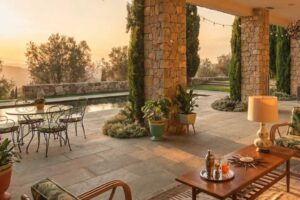 Krytá terasa historického sídla Brigitte Bardot na Francouzské riviéře s kamennými sloupy posezením a výhledem na bazén a zahradu.