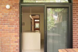 Terasa s dřevěnou podlahou a průhledem do kuchyně rodinného domu