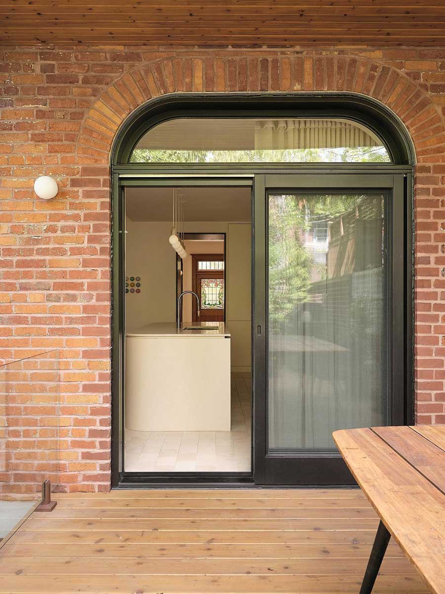 Terasa s dřevěnou podlahou a průhledem do kuchyně rodinného domu