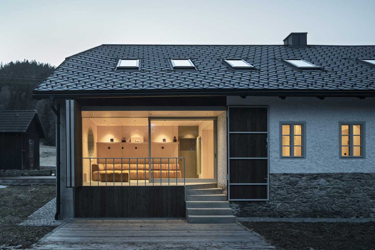 Terasa a prosklený obývací prostor večer s teplým vnitřním světlem