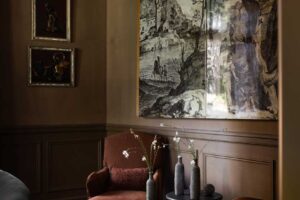 Tmavý společenský kout s čalouněnou pohovkou, historickou tapiserií a křišťálovým lustrem