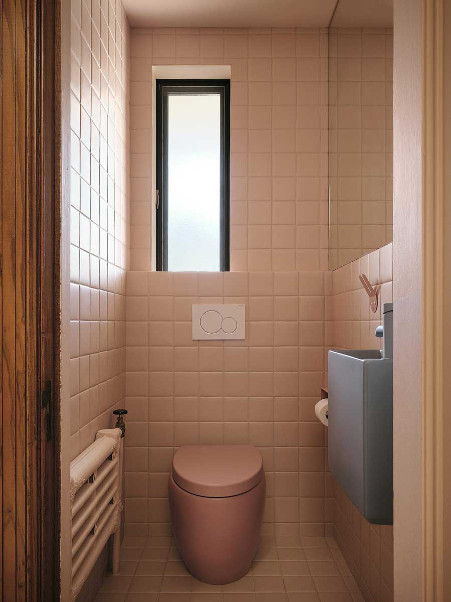 Růžová toaleta s keramickým obkladem a kompaktním sanitárním vybavením