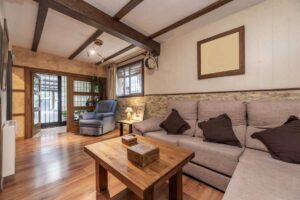 Obývací prostor s přiznanými dřevěnými trámy které vytvářejí rytmus stropu a navozují hřejivou atmosféru domova