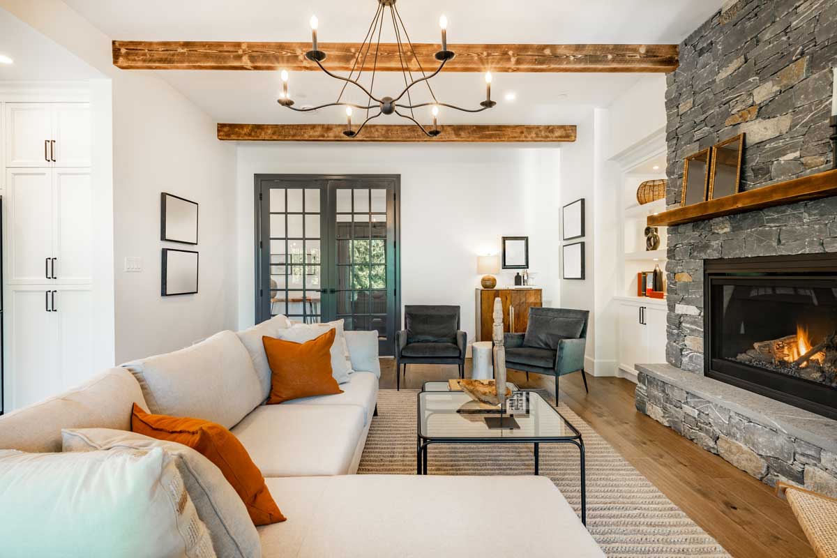 Moderní obývací pokoj s dřevěnými trámy a kamenným krbem jako dominantním historickým prvkem interiéru