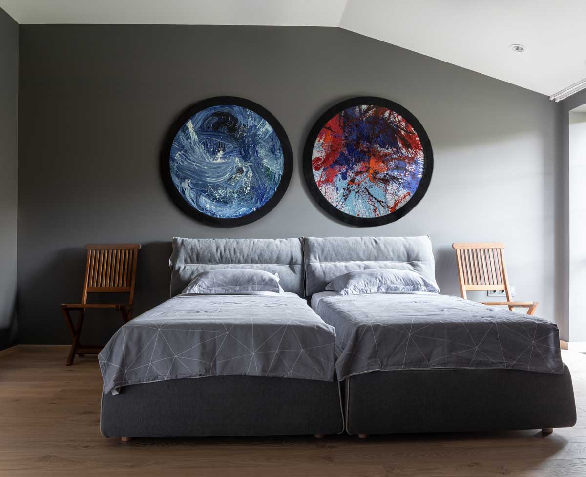 Hostovská ložnice se dvěma samostatnými lůžky, jemnými barvami a uměleckými obrazy na stěně v domě Ridnyj