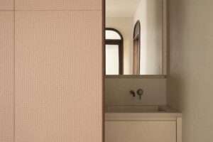 Vestavěné umyvadlo skryté za posuvným panelem v minimalistické koupelně rodinného domu