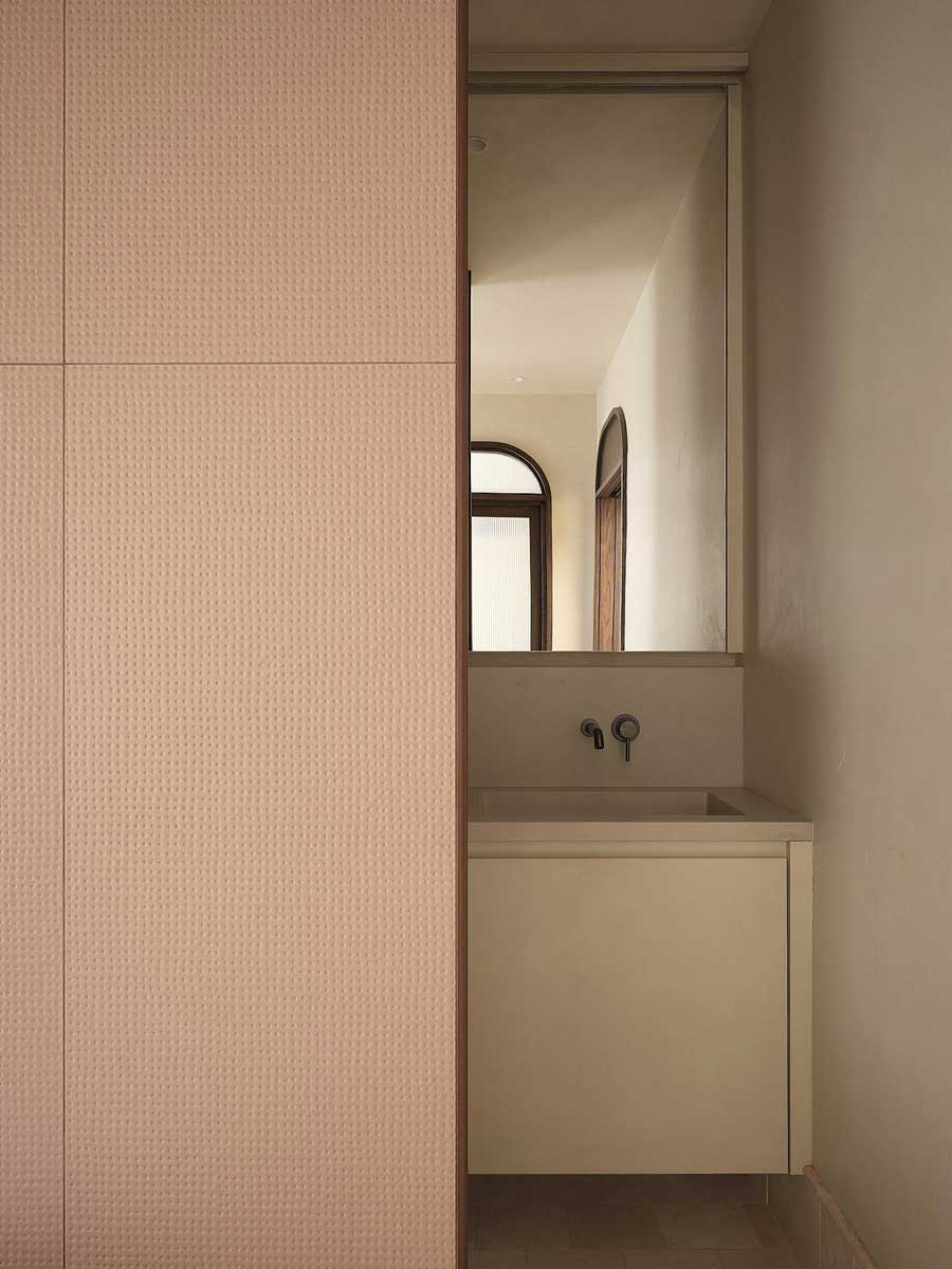 Vestavěné umyvadlo skryté za posuvným panelem v minimalistické koupelně rodinného domu