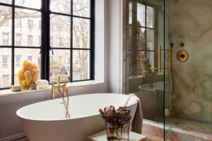 Koupelna s volně stojící vanou a sprchovým koutem obloženým přírodním kamenem