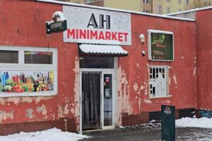 Malý místní minimarket v Orlové s oprýskanou fasádou a otevřeným vstupem v zimním období.