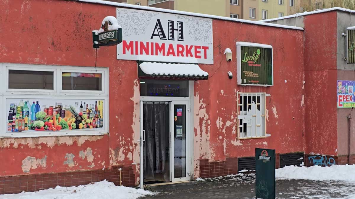 Malý místní minimarket v Orlové s oprýskanou fasádou a otevřeným vstupem v zimním období.
