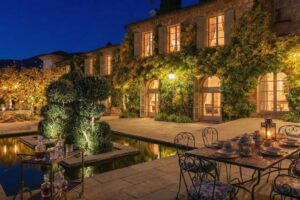 Večerní pohled na historické sídlo Brigitte Bardot na Riviéře s osvětlenou terasou zelení a venkovním posezením.