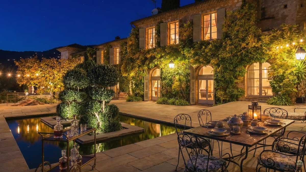 Večerní pohled na historické sídlo Brigitte Bardot na Riviéře s osvětlenou terasou zelení a venkovním posezením.