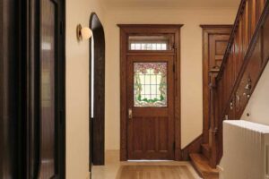 Vstupní hala rodinného domu s původním dřevěným schodištěm a vitrážovými dveřmi