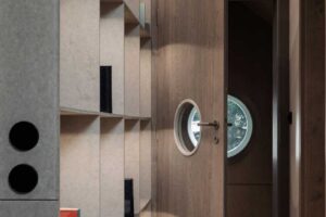 Vstupní hala s vestavěnými policemi kruhovým okénkem ve dveřích a dřevěnou podlahou