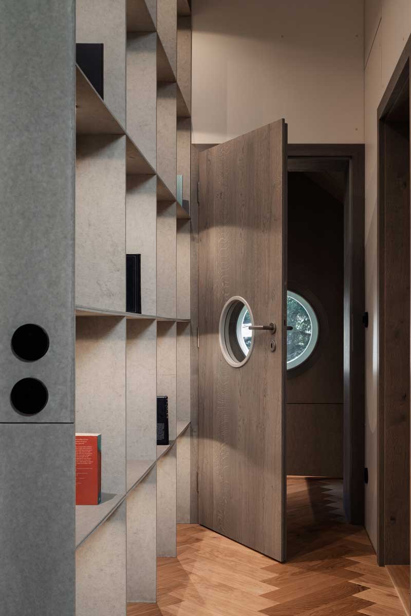 Vstupní hala s vestavěnými policemi kruhovým okénkem ve dveřích a dřevěnou podlahou