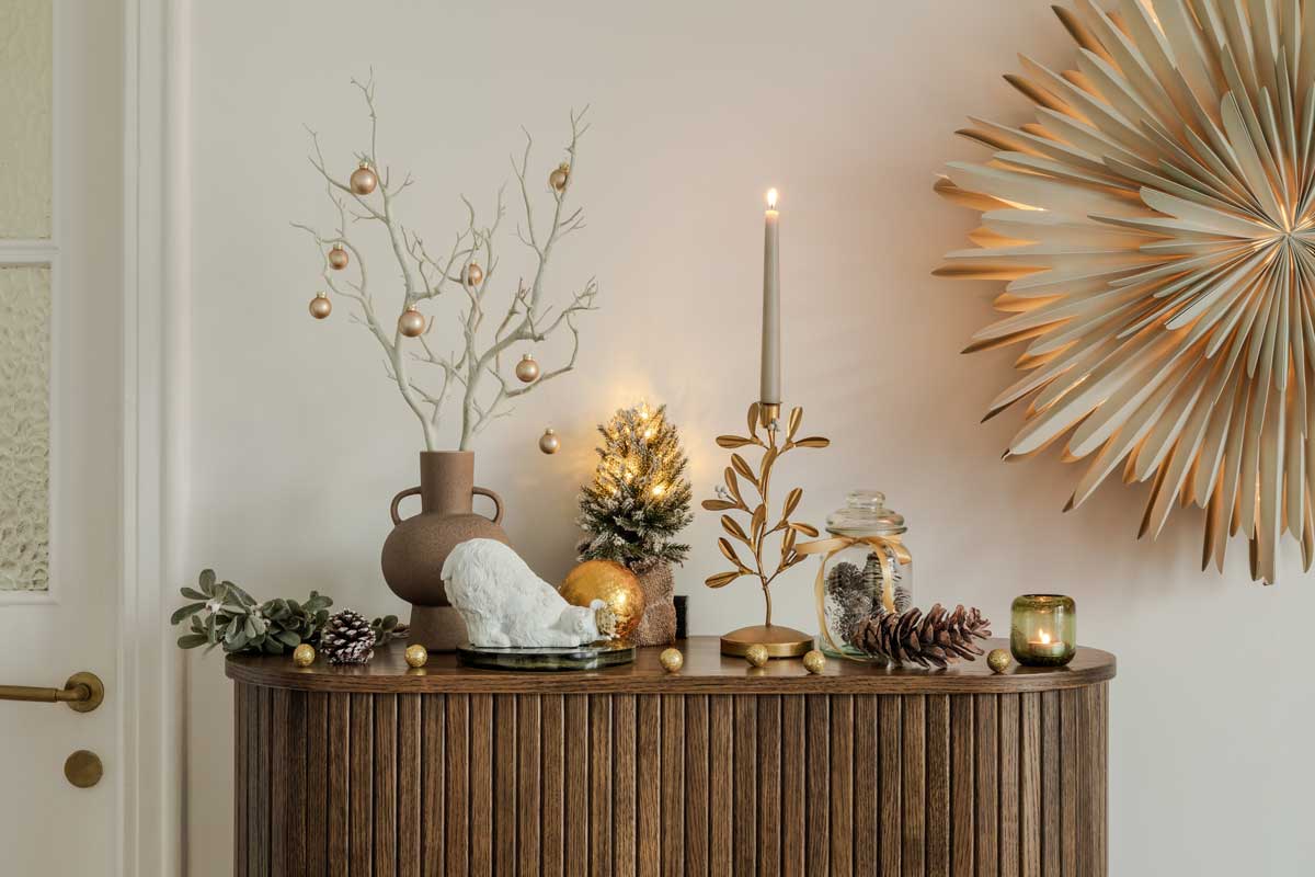 Slavnostně prostřený stůl se zlatými doplňky, svícny a dekoracemi typickými pro vánoční období