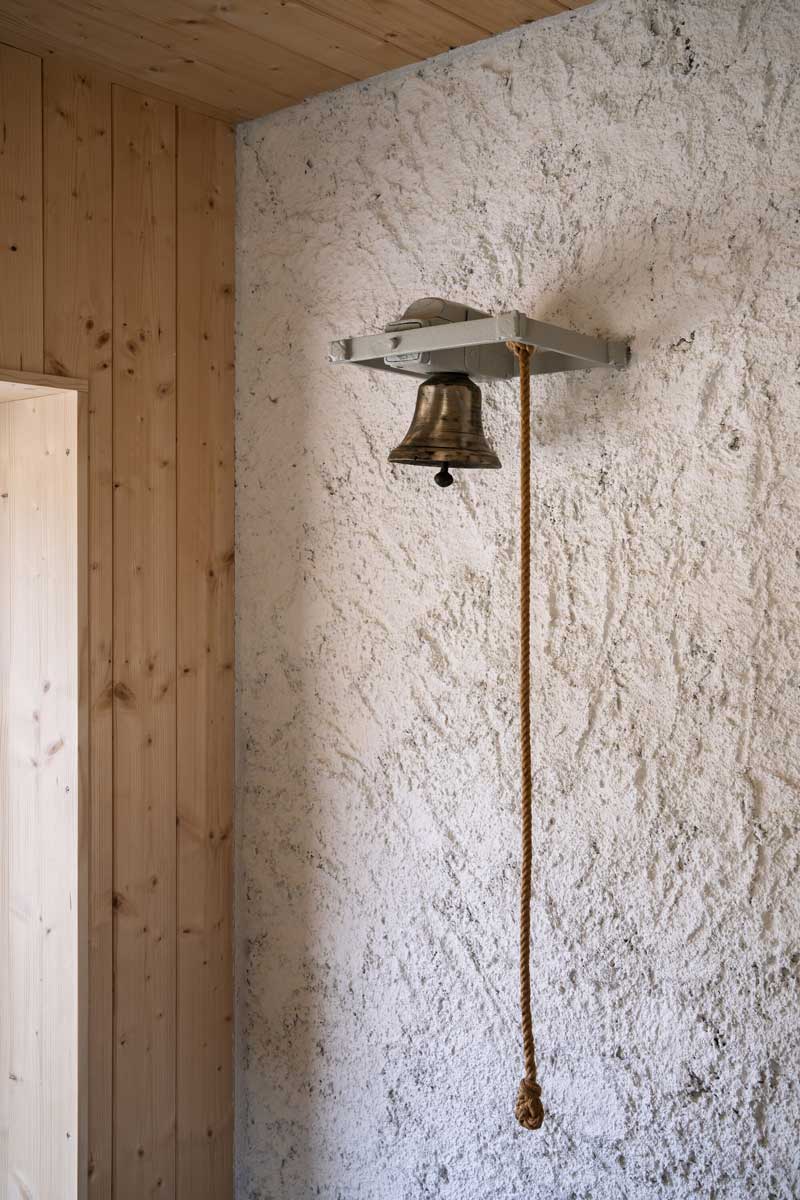 Detail zvonku s provazem na hrubé omítce v interiéru chalupy