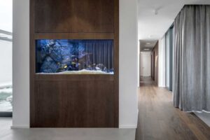 Vestavěné akvárium integrované do dřevěné stěny v moderním interiéru domu.