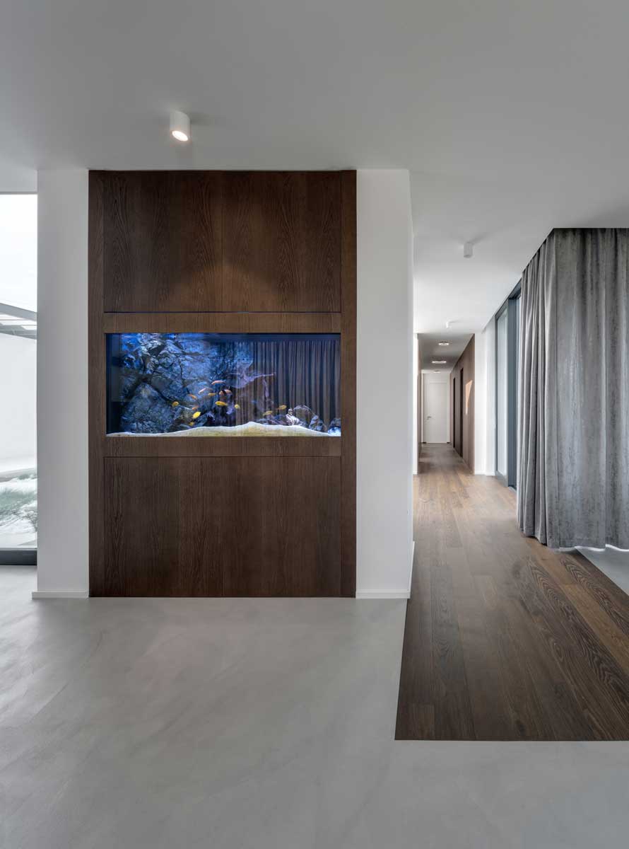 Vestavěné akvárium integrované do dřevěné stěny v moderním interiéru domu.