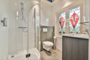 Dekorativní barevné sklo v koupelně filtruje světlo a propojuje intimitu prostoru s výtvarným akcentem inspirovaným tradicí.