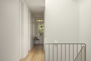 Horní chodba s jednoduchým kovovým zábradlím a světlými stěnami.