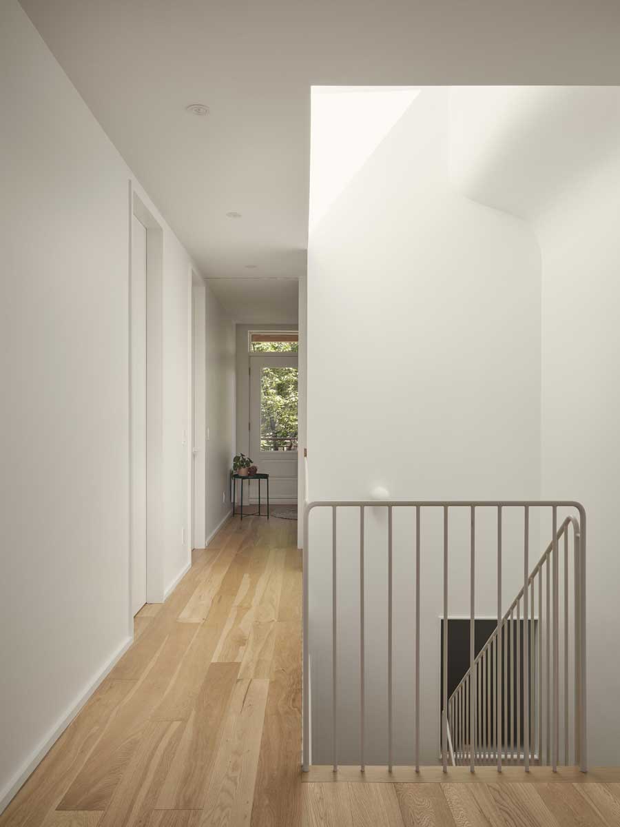Horní chodba s jednoduchým kovovým zábradlím a světlými stěnami.