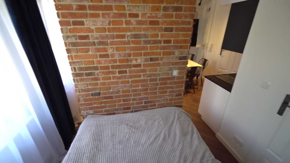 Cihlová dělící stěna v garsonce, která odděluje denní a noční zónu bez nutnosti stavět plné příčky