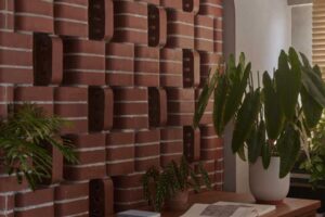 Volně stojící stěna z obloukových cihel jemně odděluje pracovní kout a zároveň umožňuje průhled do zelené části bytu.