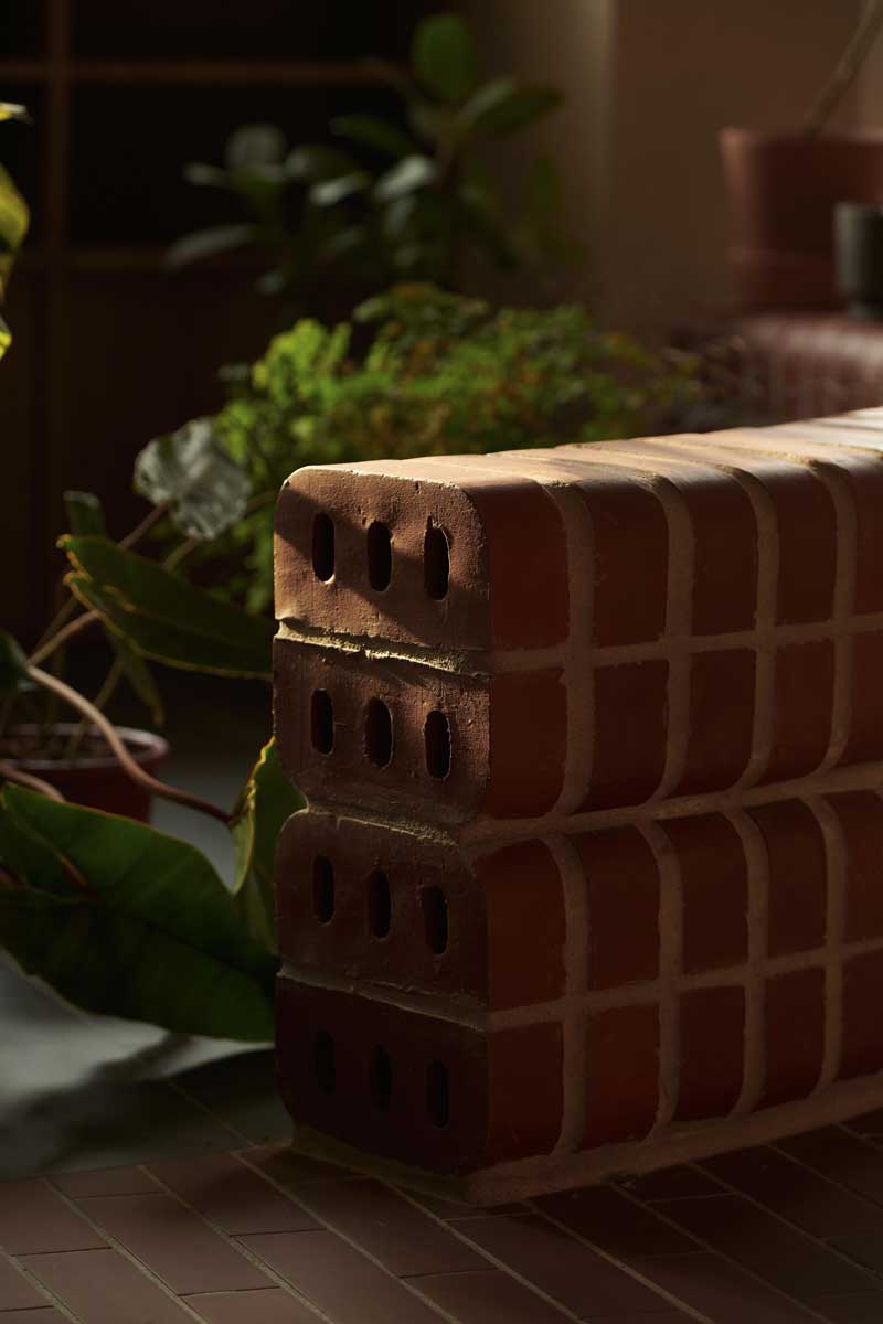 Nízká zakřivená cihlová zídka funguje jako lavička i přirozená hranice mezi jednotlivými zónami bytu.