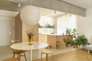 Otevřená denní zóna s kuchyní, jídelním koutem a dřevěnou podlahou v rekonstruovaném nárožním bytě