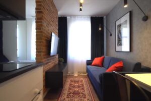 Denní zóna malého bytu sjednocená materiály a podlahou, díky nimž prostor působí větší a klidnější