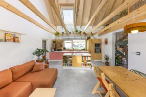 Otevřená denní zóna nízkoenergetické dřevostavby s přiznanými trámy a kuchyní prosvětlenou střešními okny