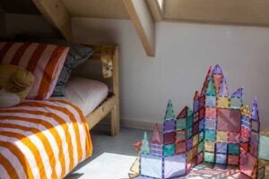 Dětský pokoj v udržitelné dřevostavbě s velkým střešním oknem a přiznanou dřevěnou konstrukcí