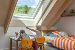 Dětský pracovní kout pod střešním oknem v nízkoenergetické dřevostavbě s důrazem na denní světlo a přirozené větrání