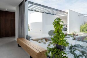 Masivní dřevěná lavice u velkoformátového okna s výhledem do zahrady.