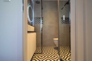 Vstup do koupelny s geometrickou dlažbou, která přidává interiéru výrazný designový akcent