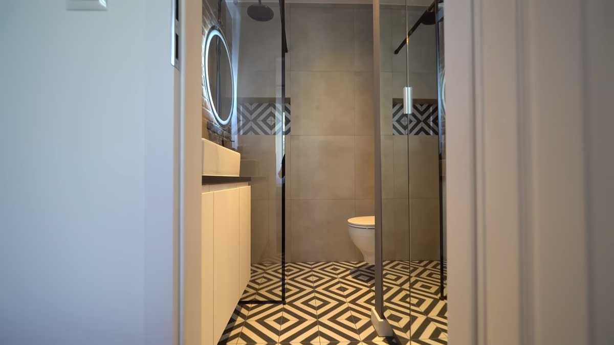 Vstup do koupelny s geometrickou dlažbou, která přidává interiéru výrazný designový akcent