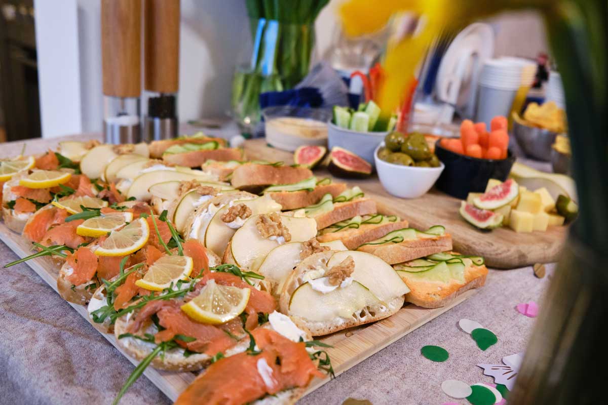 Obložené bagetky a jednohubky připravené na servírovací desce jako domácí pohoštění