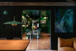 Jídelna v tmavých tónech propojuje architekturu, umění a barvy do kompaktního prostoru podporujícího kreativní setkávání.