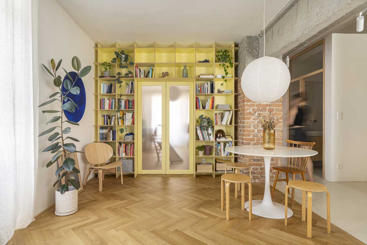 Jídelní kout s kulatým stolem a vestavěnou knihovnou v otevřeném obytném prostoru