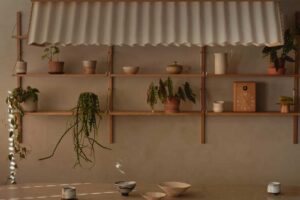 Minimalistická jídelní sestava doplněná otevřenými policemi a rostlinami vytváří harmonické spojení funkčnosti a vizuální lehkosti.