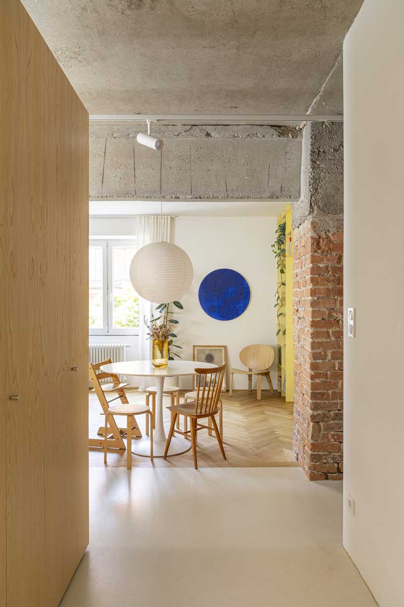 Kulatý jídelní stůl umístěný v otevřeném prostoru mezi kuchyní a obývacím pokojem