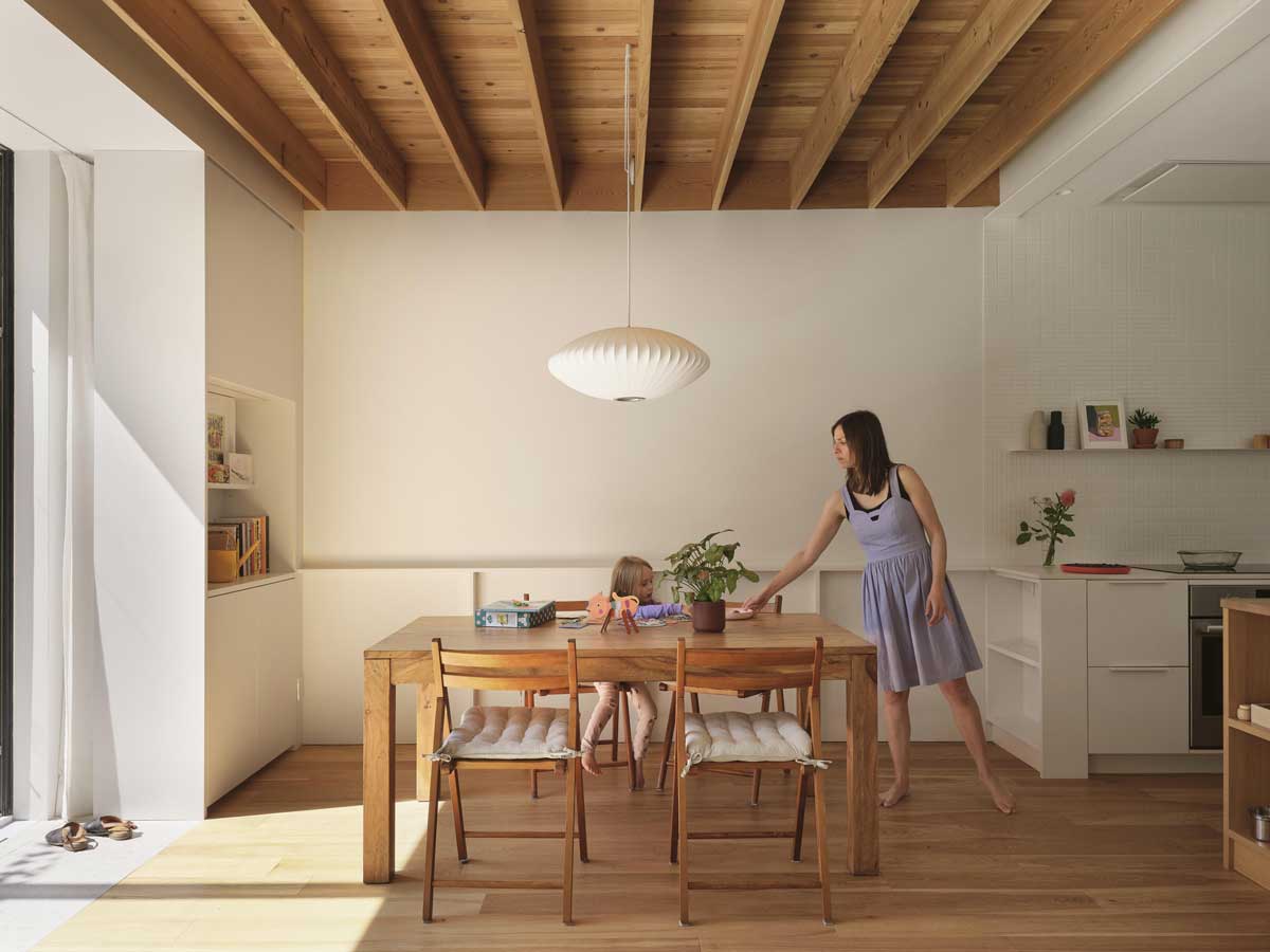 Jídelní kout s masivním stolem pod dřevěným stropem a výhledem do zahrady.