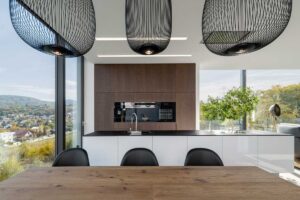 Jídelní kout s masivním dřevěným stolem, černými designovými židlemi a panoramatickým oknem.