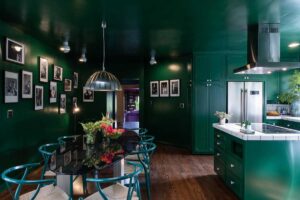 Tmavě zelená kuchyně s jídelním stolem vytváří intenzivní barevné prostředí, které podporuje soustředění i kreativní atmosféru domu Zappa Nest.