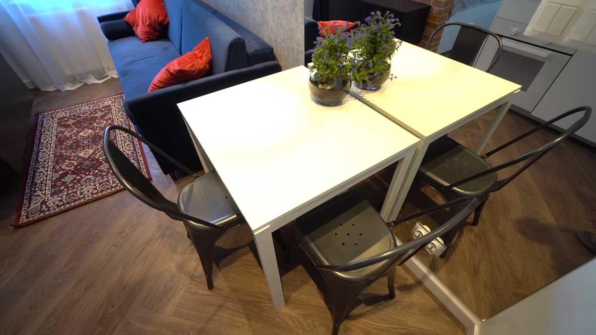 Jídelní stůl se zrcadlovou stěnou v malé garsonce, který opticky zvětšuje prostor