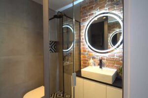 Moderní koupelna s walk-in sprchovým koutem a cihlovým obkladem v malém bytě